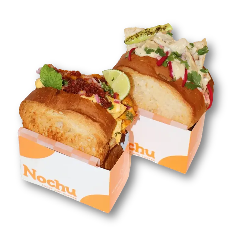 Dos toasts de Nochu en sus cajas: uno con chorizo, cebolla morada y hierbabuena; otro con pollo, rábano y cilantro